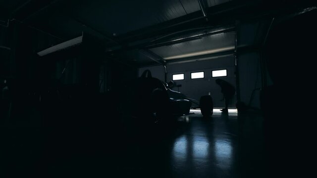 Mechanics are closing garage with a racing car inside