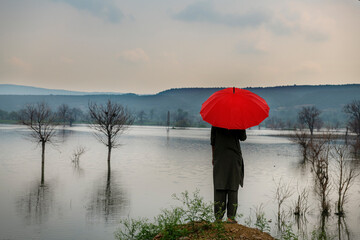 man with red umbrella on the bank of river 