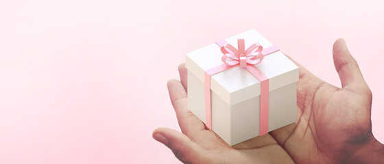Gift Box and hands holding a small gift wrapped with pink ribbon. Season of Giving Concept on pink background. birthday, valentine's day, Christmas -3d Rendering