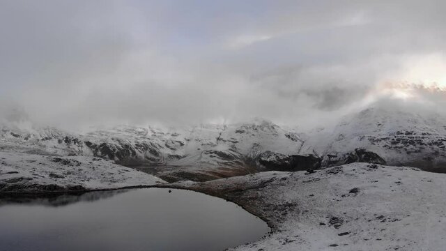 Flying above frozen Lake, towering snowy Peak, blue sky.