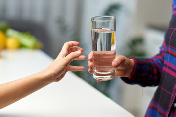 Frame image of a little girl hand holding a glass of water in the kitchen with the young mother.