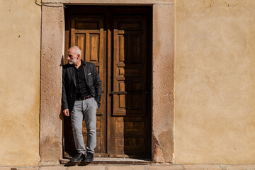 Obraz na płótnie Canvas Man in black suit standing in front of wooden door against wall