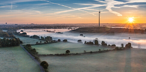 Sunrise and the first rays of sunshine over the fog-covered Ruhr meadows in Duisburg, Germany