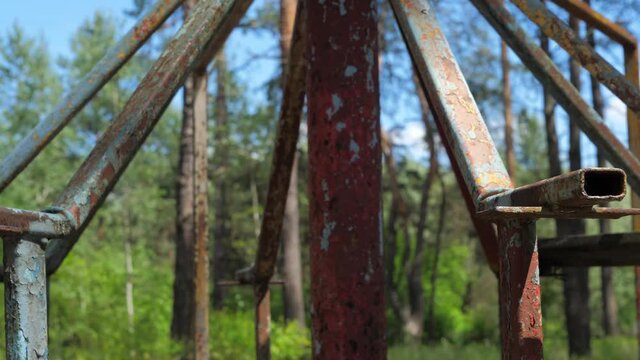 close-up, detail of the seat of an old rusty carousel rotating counterclockwise against the background of a pine forest