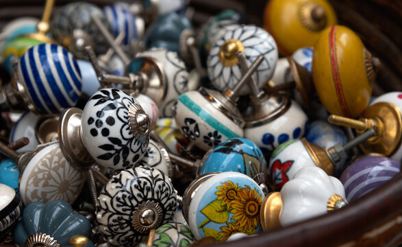 Old fashioned ornate ceramic door knobs at flea market in Paris, France. Vintage furniture design background. Closeup. Selective focus.