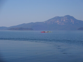 Calm surface of the lake and sportsmen on a kayak