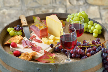 Südtiroler Marende mit klassischen Spezialitäten auf einem Weinfaß dazu regionaler Rotwein -...