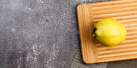 Quince on a rectangular cutting wooden board on a dark background. Top view, flat lay