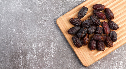 Dates on a rectangular cutting wooden board on a dark background. Top view, flat lay