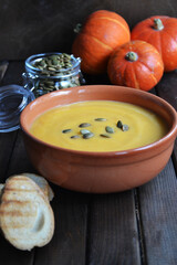 pumpkin soup with toast and seeds on a dark background in a brown plate