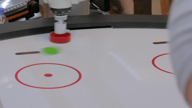 Robotic arm manipulator playing air hockey at robot exhibition, trade show - close up view. Ai, sport, game, competition, technology concept