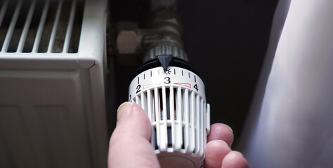 turning down thermostat on radiator to save energy due to heating cost price hike - obrazy, fototapety, plakaty