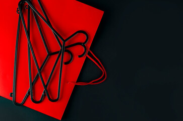 Black hanger and red bag on black background. Black friday sale concept. Copy space