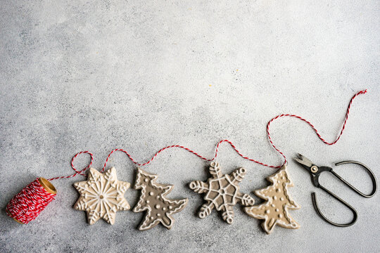Making Christmas gingerbread cookie ornaments with string and scissors