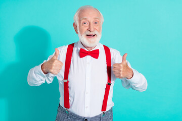 Portrait of attractive cheerful grey-haired mister showing two thumbup advert isolated over bright teal turquoise color background