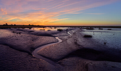 tidal ways in the mud flats at Langwarder Groden (Butjadingen, Germany) under a scenic colorful sunset sky during low tide