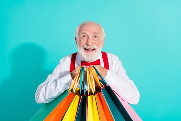 Portrait of attractive cheerful grey-haired man buying new things clothes looking up isolated on...