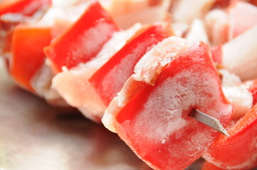 Close up of frozen raznjici with meat, bacon, onion and paprika on metal skewers ready to grill