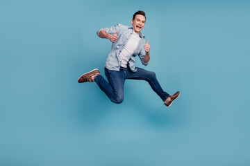 Fototapeta na wymiar Full size profile side photo of young man jump show fingers thumbs-up select suggest ad isolated over blue color background