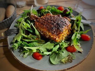 Lasagne with mixed leaf salad and tomatoes next to a bread basket