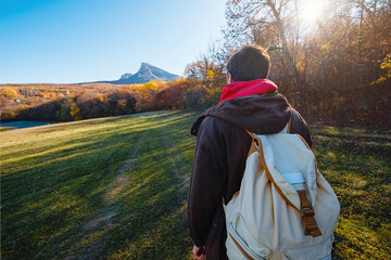 man in autumn woods, fantasy forest landscape. man wearing backpack standing on autumn forest trail, hiking alone, copy space