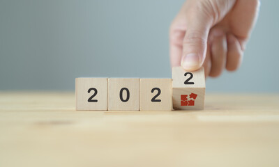 Business strategy and game plan in 2022 concept. Businessman hand flips wooden cubes "2022" and "strategy" symbol  on beautiful  background and copy space. For the new year action plan and execution.