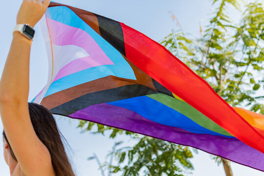 Progress pride flag (new design of rainbow flag) waving in the air with blue sky, Celebration of gay pride, The symbol of lesbian, gay, bisexual and transgender, LGBTQ community