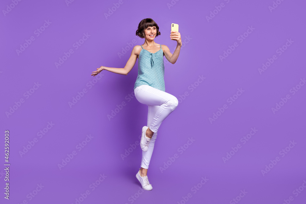 Wall mural Full length body size view of lovely cheery girl taking selfie jumping having fun isolated over bright purple violet color background