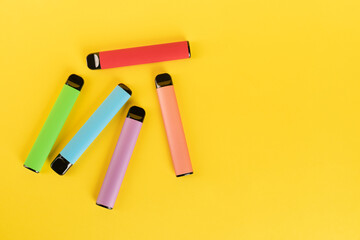 Layout of colorful disposable electronic cigarettes on a yellow background. The concept of modern...