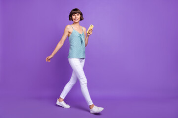 Fototapeta na wymiar Full length body size view of attractive cheerful girl going using device isolated over bright violet purple color background