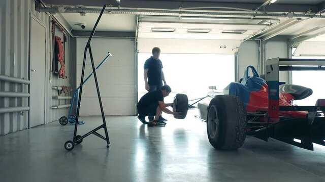 Specialists are fixing wheels of a racing car at the garage