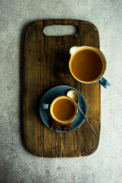 Overhead view of a cup of turmeric tea and jug on a chopping board