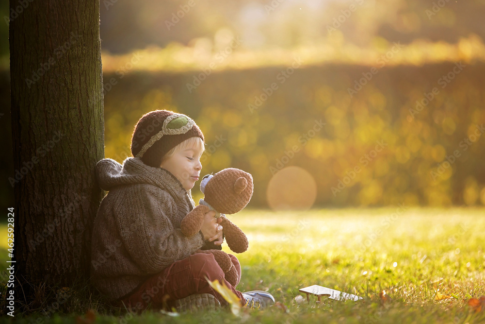 Poster Little toddler child, boy, playing with airplane and knitted teddy bear in autumn park