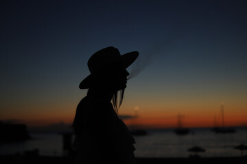 silhouette of young girl smoking at sunset
