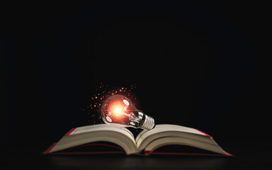 Lightbulb glowing on book over dark background for creative thinking idea after reading and study...