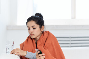 woman taking cover with plaid at home medication glass with water