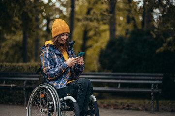 Woman in wheelchair using a smartphone while out in the city park