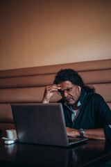 Senior hispanic cuban men using a laptop while having a headache from work stress