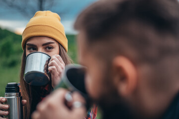 Naklejka premium Couple of campers drinking coffee from a metal cups
