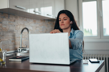 Businesswoman using airpods and a laptop while working from home