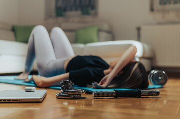 Young attractive tired woman lying on a fitness mat after training at home