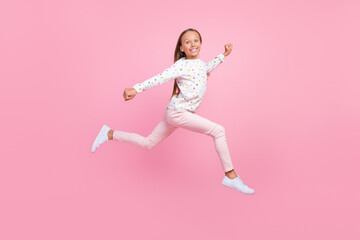 Fototapeta na wymiar Photo of sporty little lady jump run hurry wear dotted pajama trousers sneakers isolated pink color background