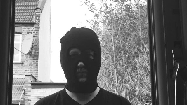 creepy man at window in balaclava mask concept of danger intruder