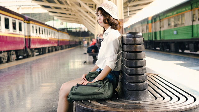 Happy Asian woman waiting the train at train station for travel in summer. Travel Thailand concept.