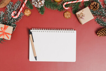 Minimal creative flat lay of winter christmas traditional composition and new year holiday season. Top view open mockup black notebook for text on red background. Mock up and copy space photography.