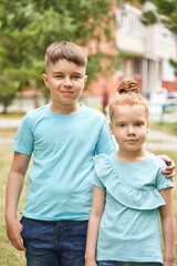 Little girl and boy at backyard. Green casual dress. Family outdoor portrait. Female and male children. Summer day. Happy sibling faces. Friendship concept.