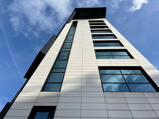 Looking up at a modern building with a cloudy blue sky background. Taken in Manchester England. 
