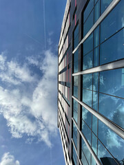 Looking up at a modern building with a cloudy blue sky background. Taken in Manchester England. 