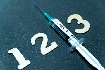 Third covid vaccine dose and jab concept with numbers. Syringe is seen on table as a concept for...