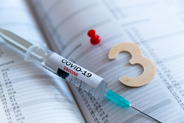 Third covid vaccine dose and jab concept. Three syringes are seen on calendar as a concept for the 3rd covid-19 vaccine dose, also called booster shot, now requested during the vaccination campaign. - obrazy, fototapety, plakaty